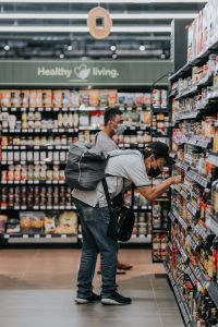 Chinese man grocery shopping in a pandemic, looking at canned food with a mask on