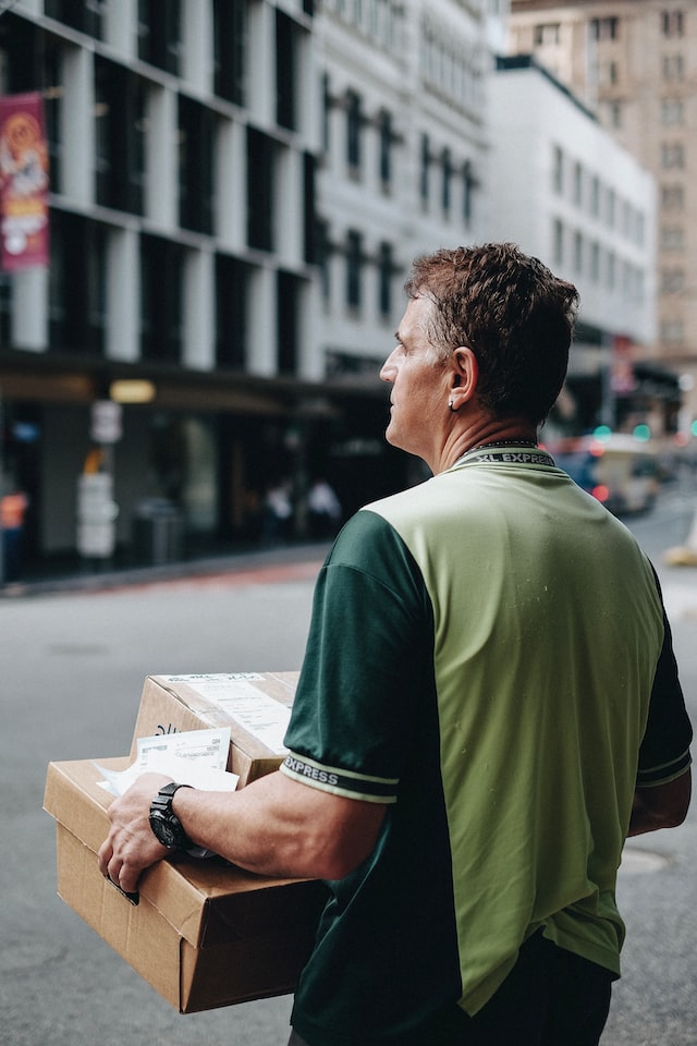 Man carrying cardboard boxes during daytime